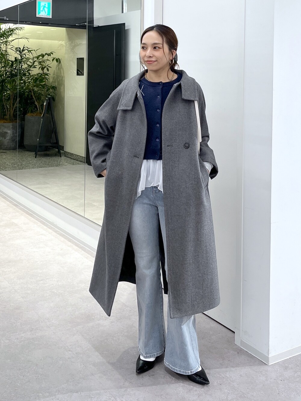 ホワイト系のTシャツ/カットソー、グレー系のステンカラーコート、ブルー系のニット/セーターを着用したレディースの秋コーディネートの6枚目の写真