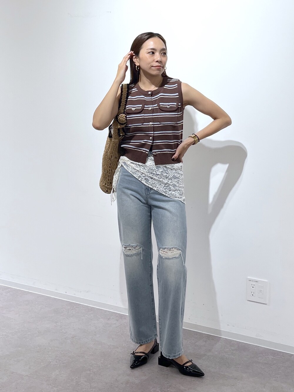 ブラウン系のニット/セーター、ブラック系のパンプス、ブルー系のデニムパンツを着用したレディースの夏コーディネートの8枚目の写真