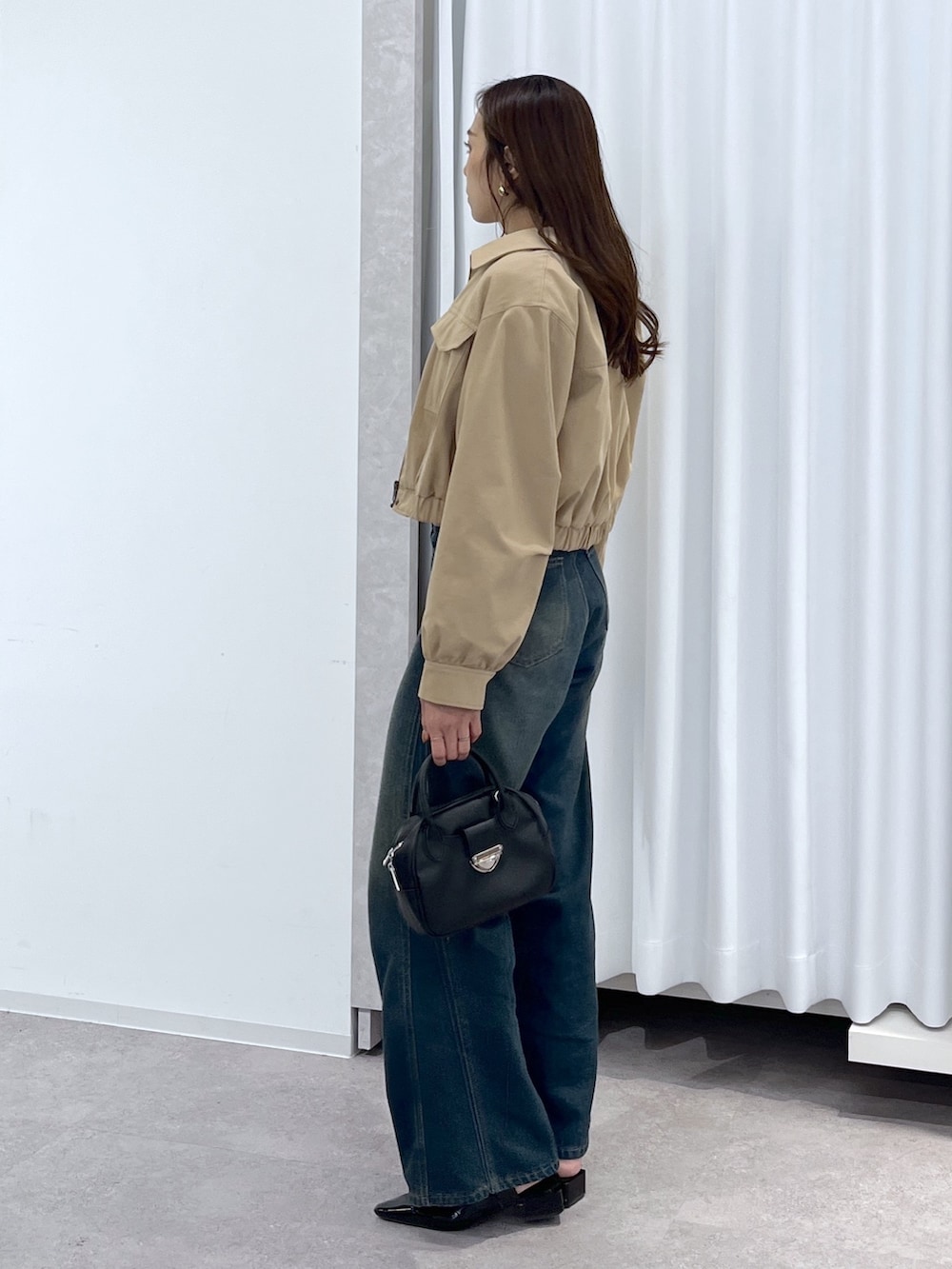 ベージュ系のブルゾン、ホワイト系のニット/セーター、ブルー系のデニムパンツを着用したレディースの春コーディネートの3枚目の写真