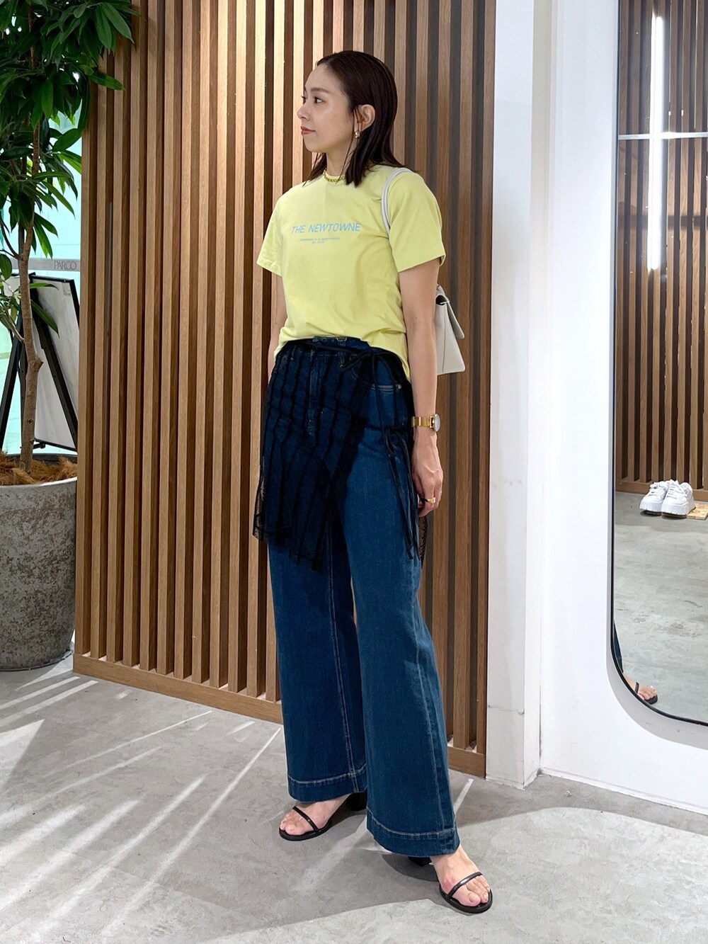 イエロー系のTシャツ/カットソー、ホワイト系のショルダーバッグ、ブラック系のスカートを着用したレディースの夏コーディネートの4枚目の写真