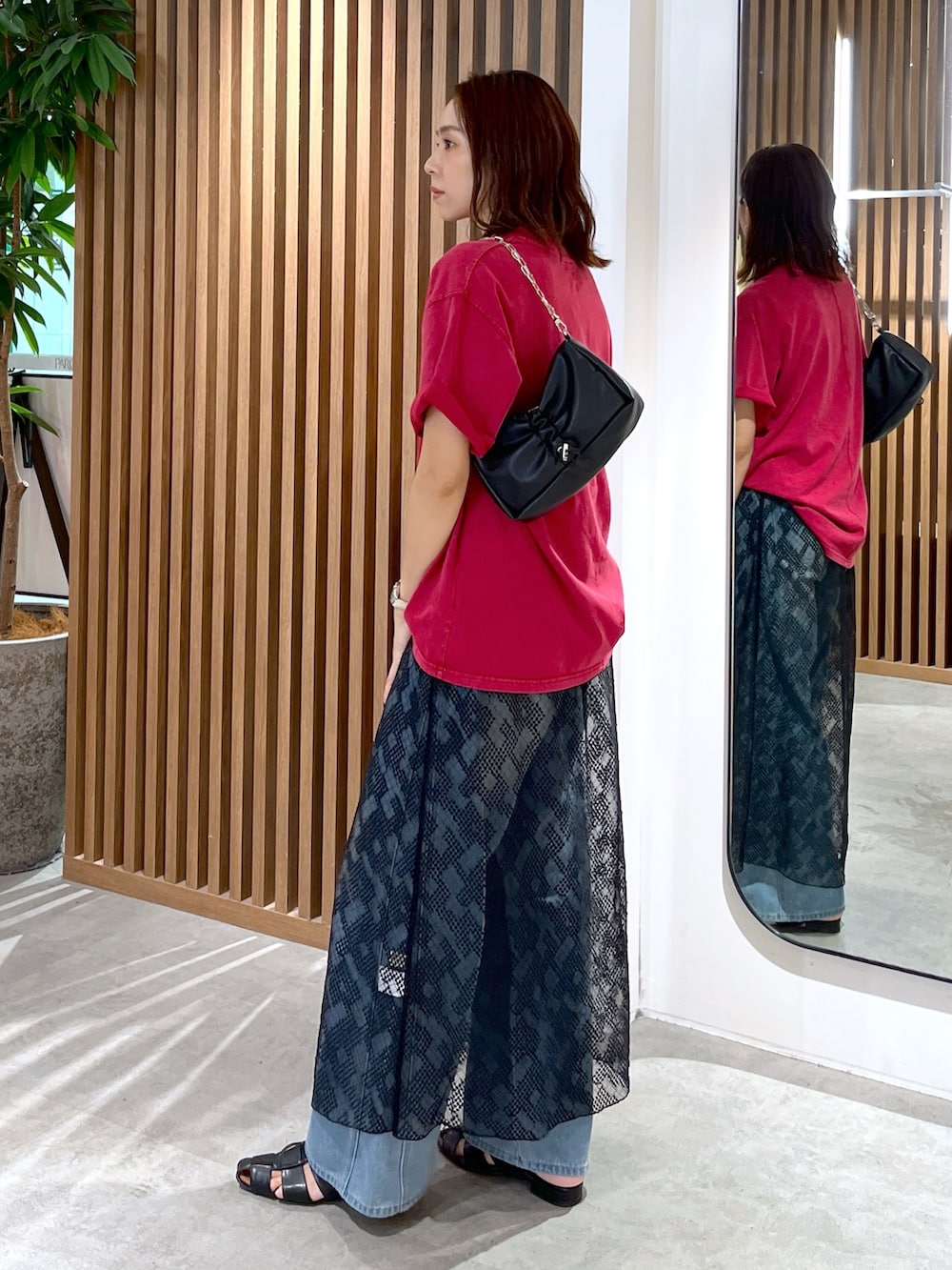 レッド系のTシャツ/カットソー、ブラック系のハンドバッグ、ブルー系のデニムパンツを着用したレディースの夏コーディネートの4枚目の写真