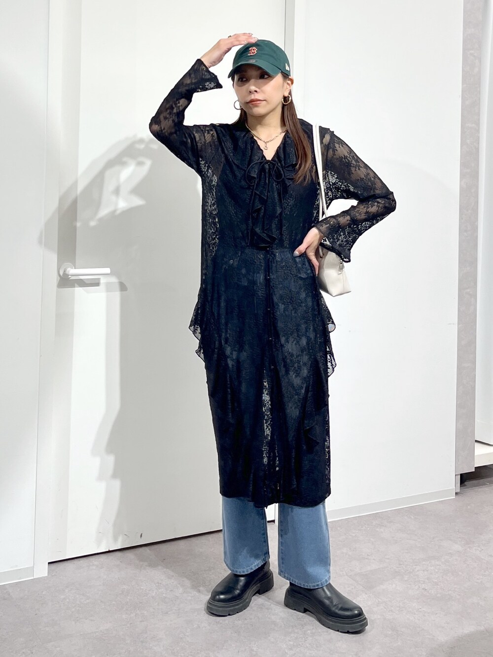 ホワイト系のショルダーバッグ、ブラック系のワンピース、ブルー系のデニムパンツを着用したレディースの冬コーディネートの9枚目の写真