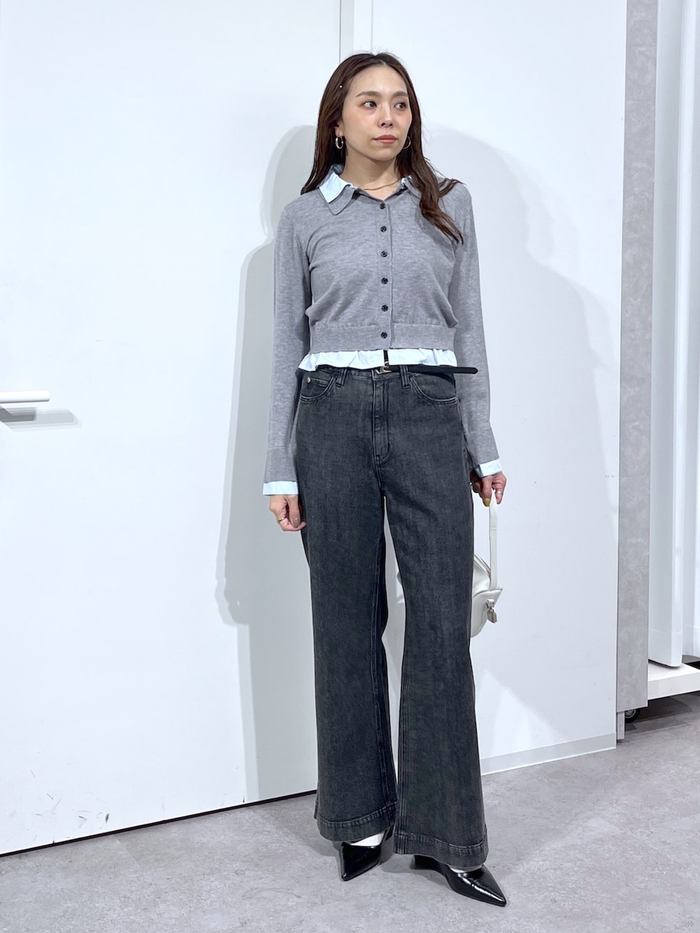 グレー系のニット/セーター、ホワイト系のハンドバッグ、ブラック系のデニムパンツを着用したレディースの春コーディネートの10枚目の写真