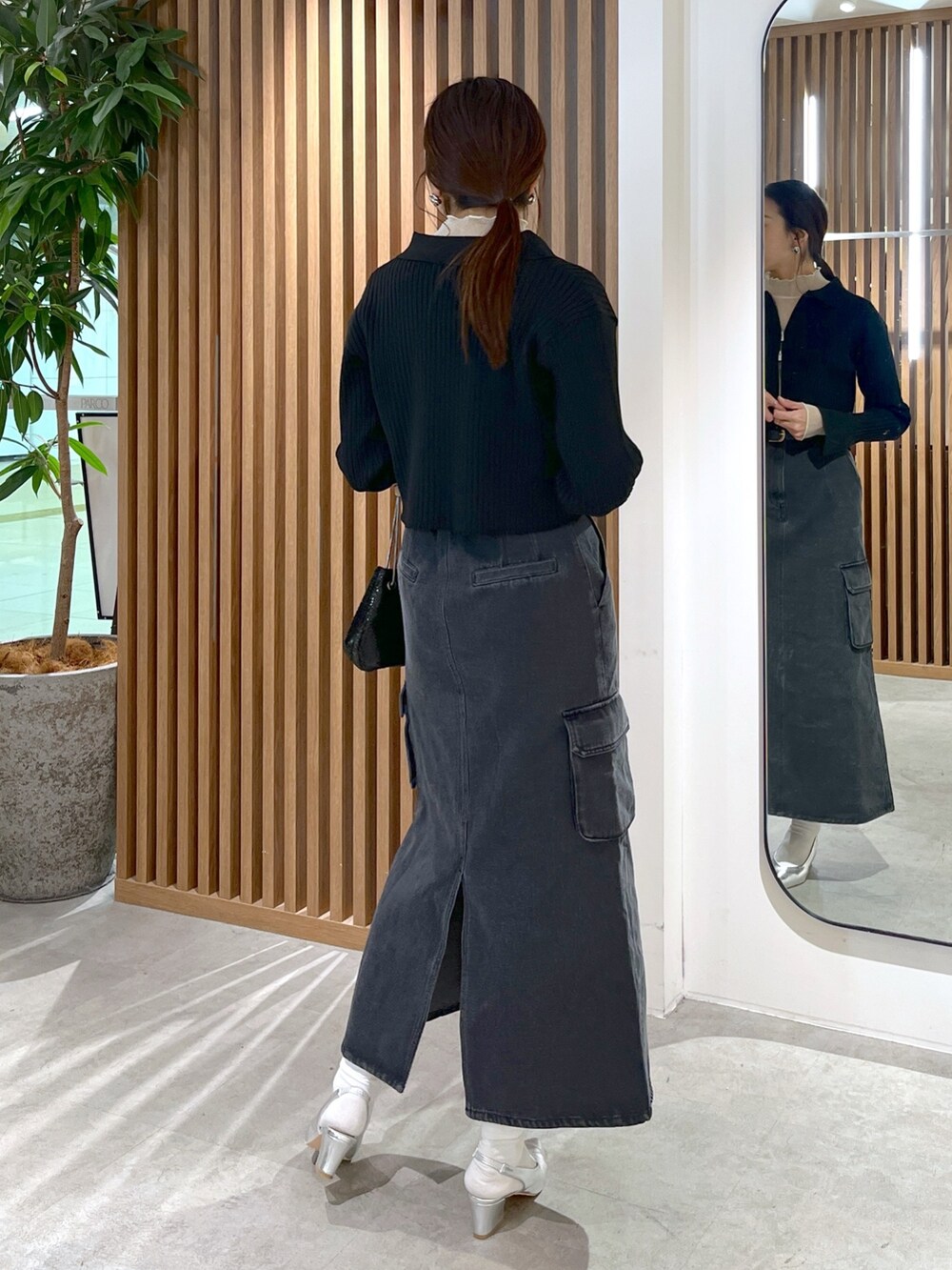 ブラック系のニット/セーター、ホワイト系のTシャツ/カットソー、ブラック系のショルダーバッグを着用したレディースの冬コーディネートの5枚目の写真