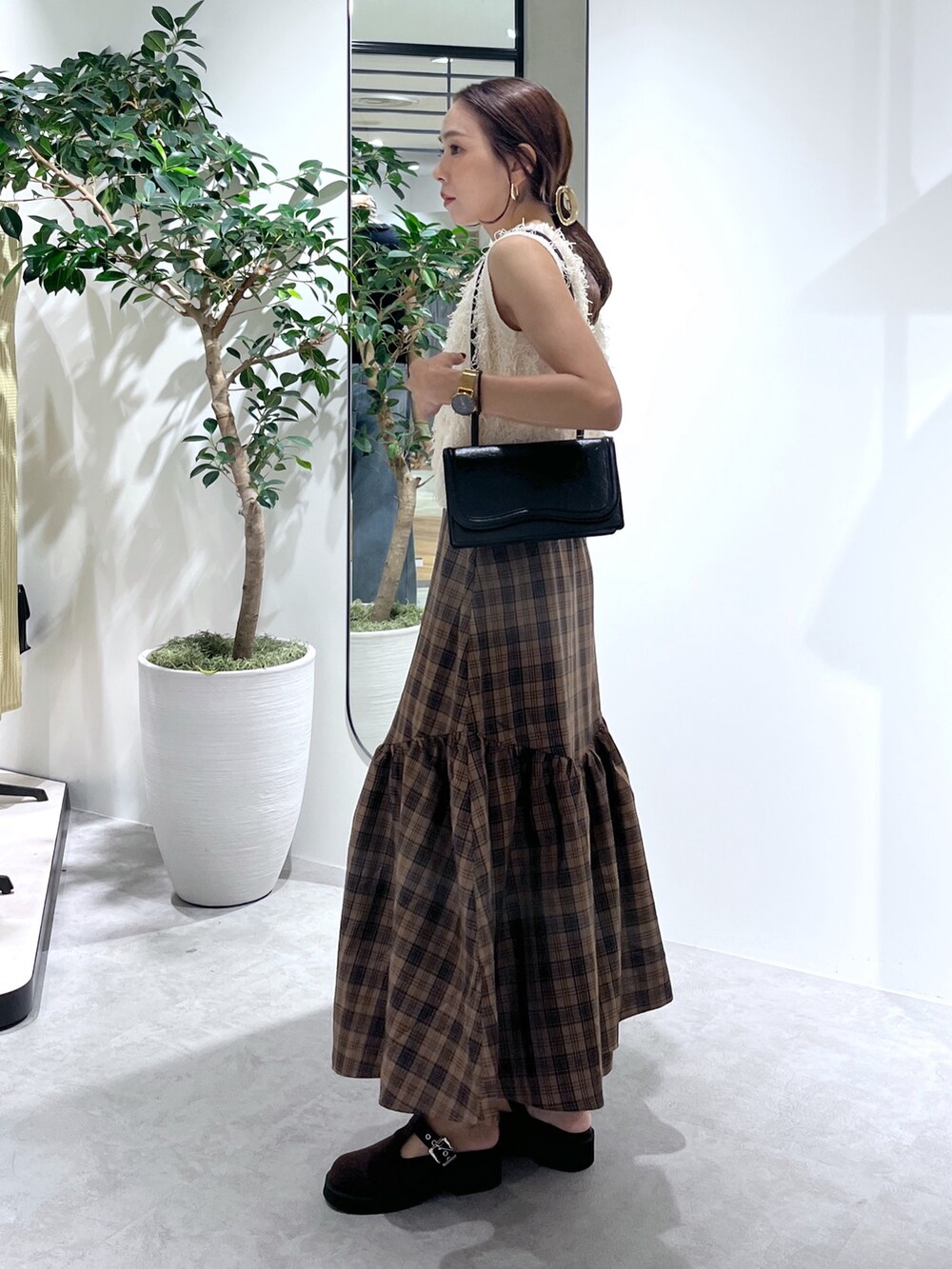 ブラウン系のシューズ、ブラック系のショルダーバッグ、ホワイト系のニット/セーターを着用したレディースの夏コーディネートの3枚目の写真