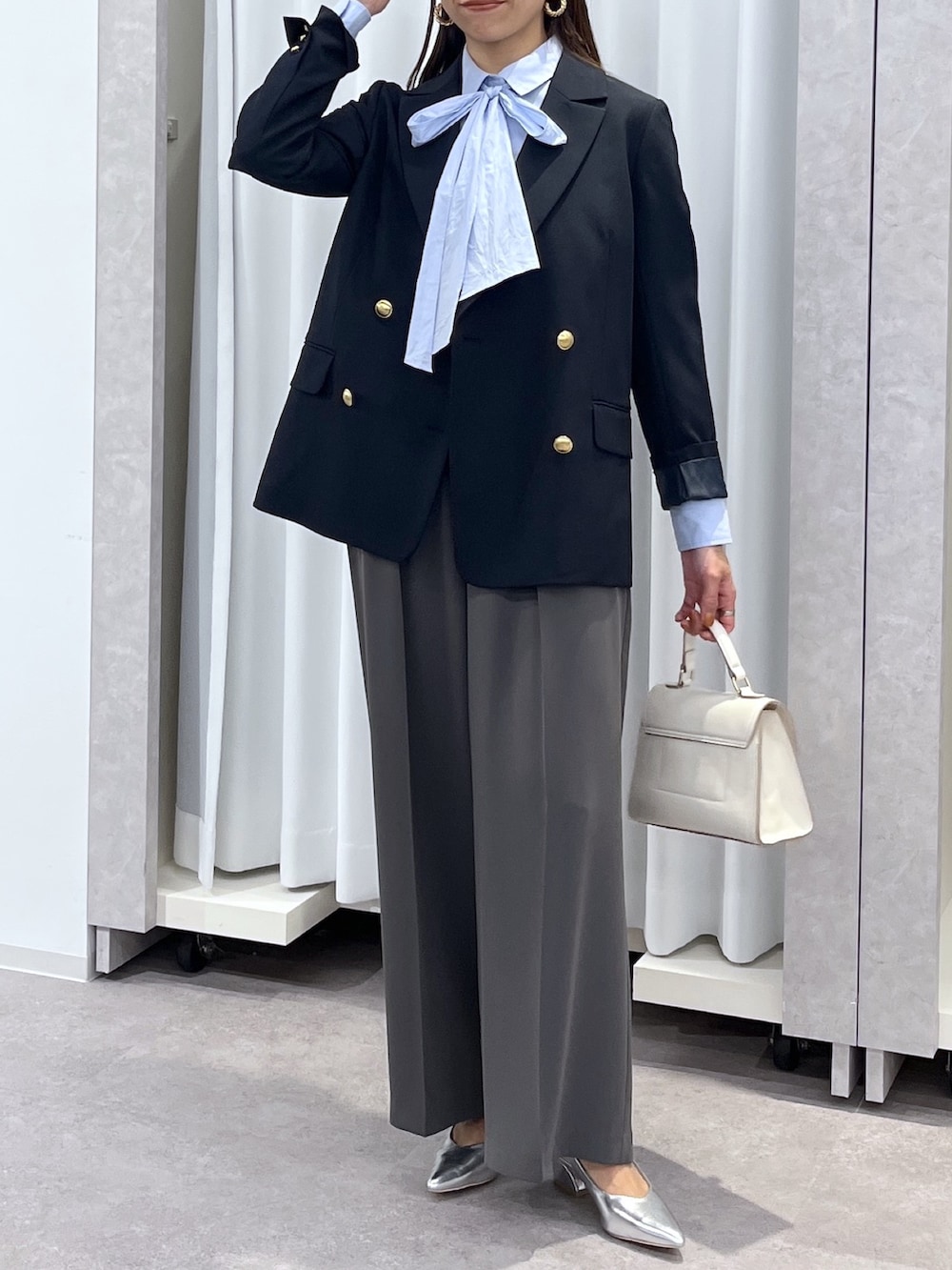 シルバー系のパンプス、グレー系のスラックス、ホワイト系のショルダーバッグを着用したレディースの冬コーディネートの5枚目の写真