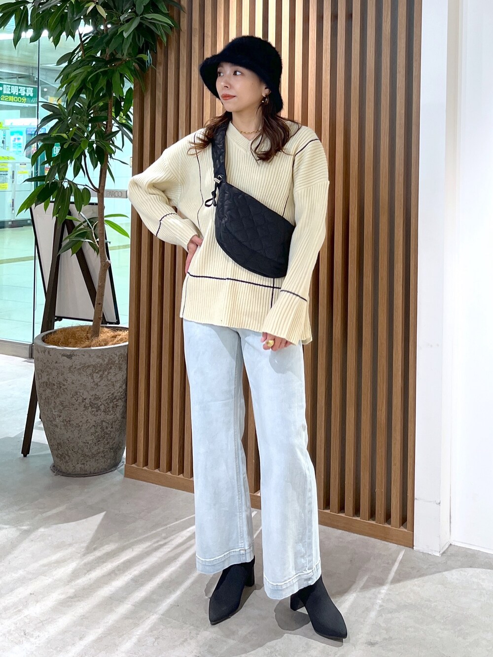 ブラック系のショルダーバッグ、ホワイト系のニット/セーター、ブルー系のデニムパンツを着用したレディースの冬コーディネートの2枚目の写真
