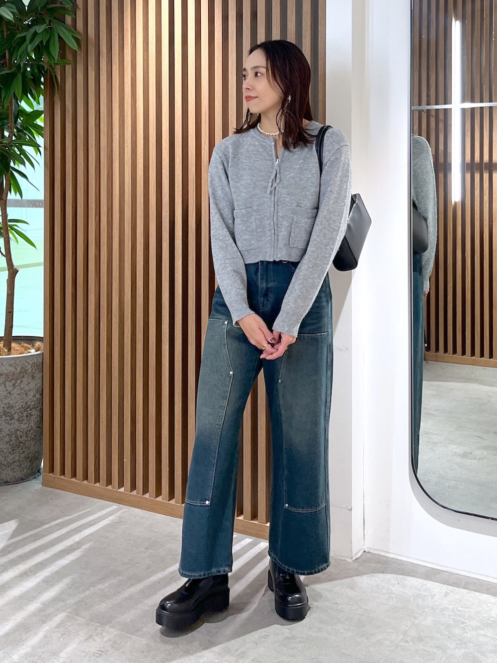グレー系のワンピース、ブルー系のデニムパンツ、ブラック系のブーツを着用したレディースの冬コーディネートの3枚目の写真