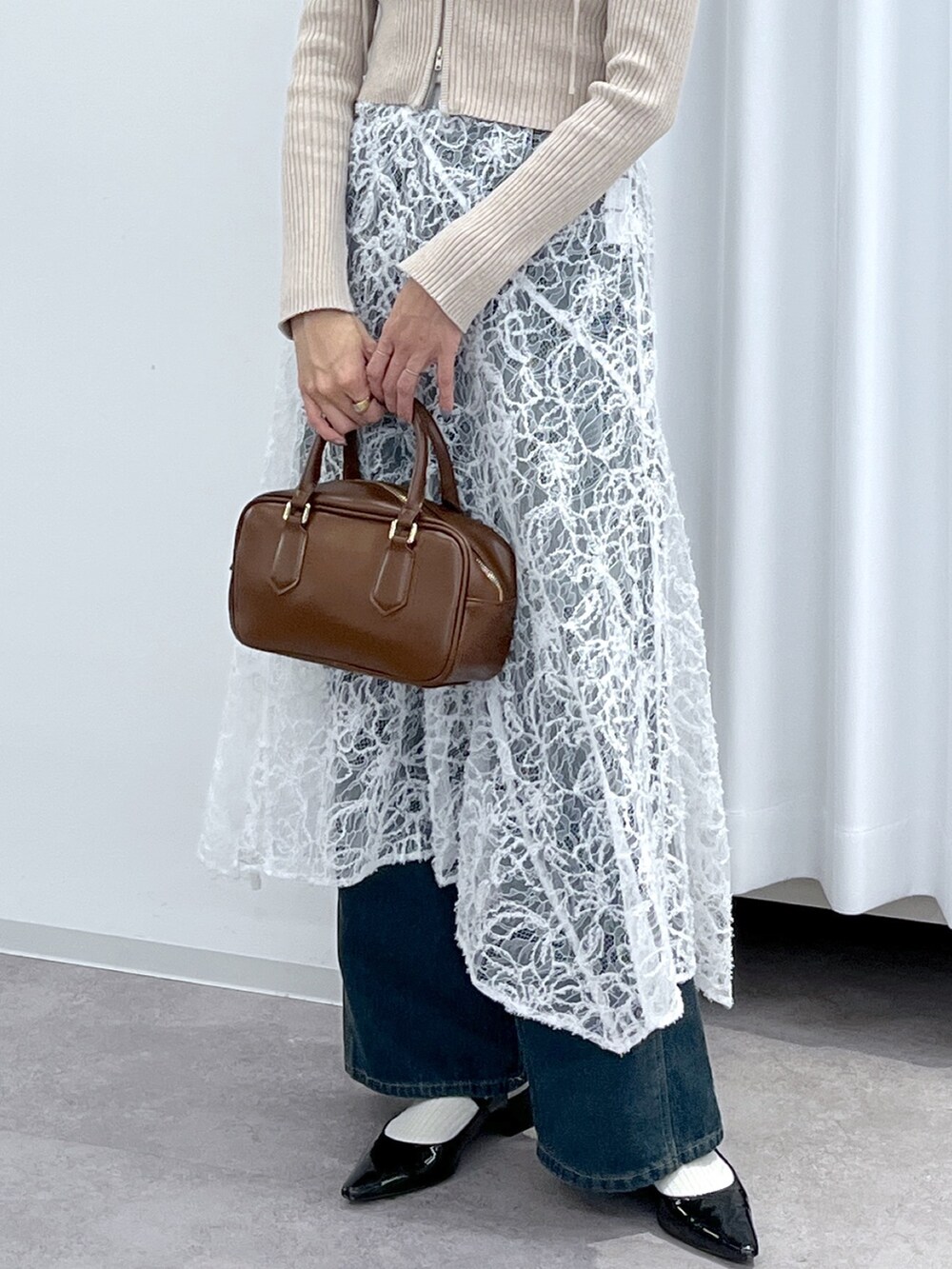 ベージュ系のニット/セーター、ブラウン系のハンドバッグ、ブルー系のデニムパンツを着用したレディースの冬コーディネートの7枚目の写真