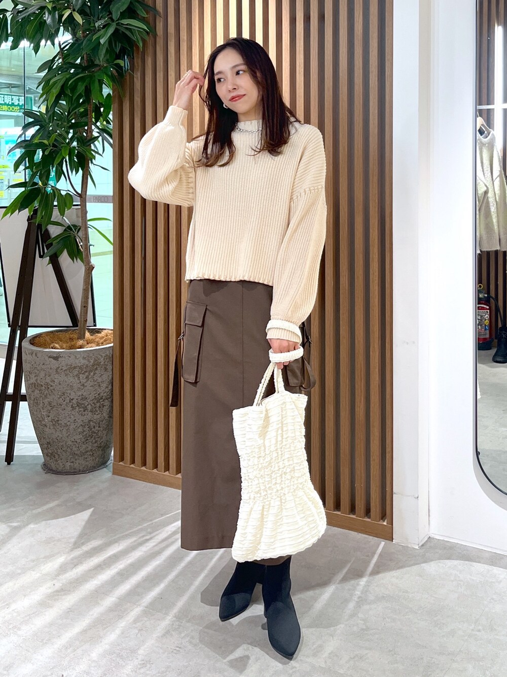ブラウン系のスカート、ホワイト系のトートバッグ、ホワイト系のニット/セーターを着用したレディースの冬コーディネートの6枚目の写真