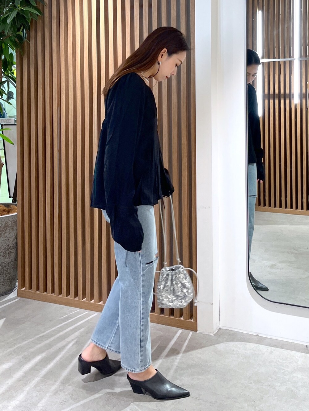 ブラック系のシャツ/ブラウス、ブルー系のデニムパンツ、シルバー系のハンドバッグを着用したレディースの冬コーディネートの4枚目の写真