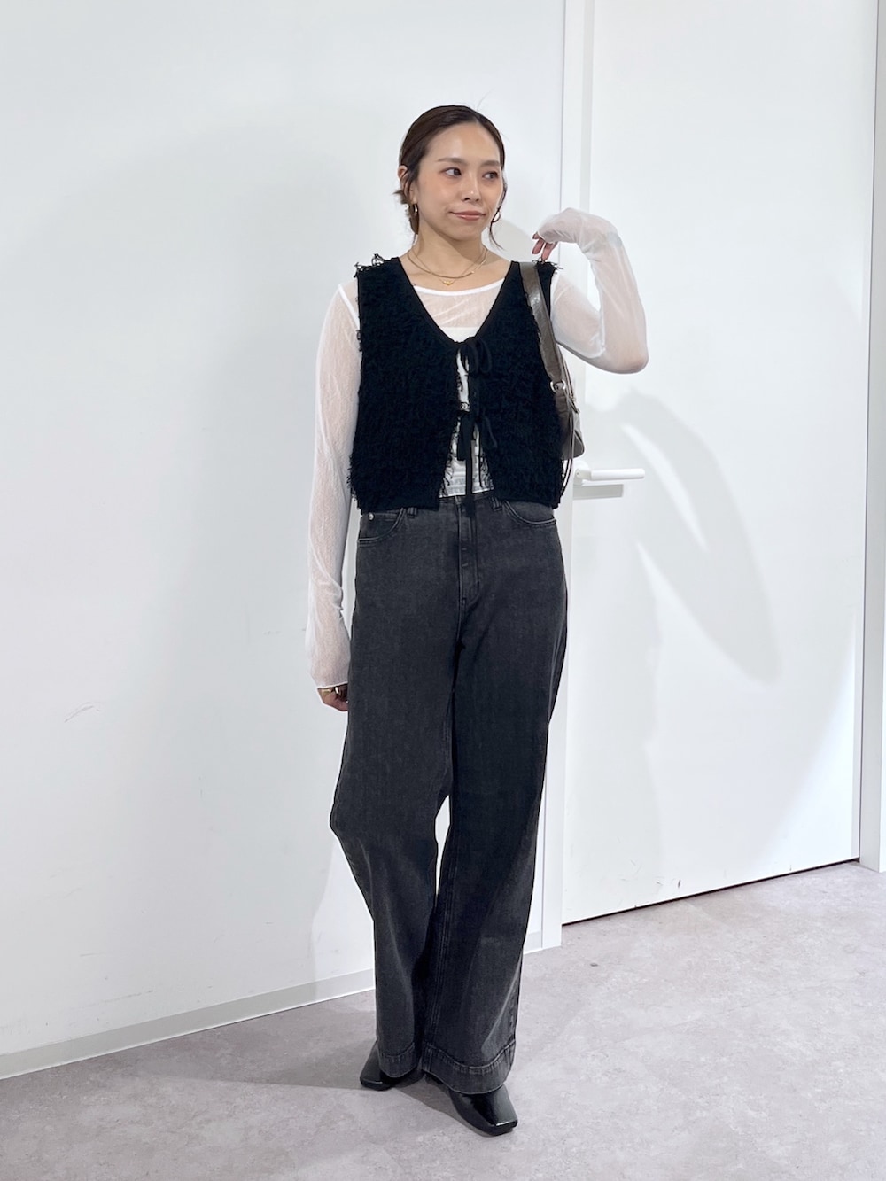 ブラウン系のショルダーバッグ、ブラック系のニット/セーター、ホワイト系のTシャツ/カットソーを着用したレディースの夏コーディネートの7枚目の写真