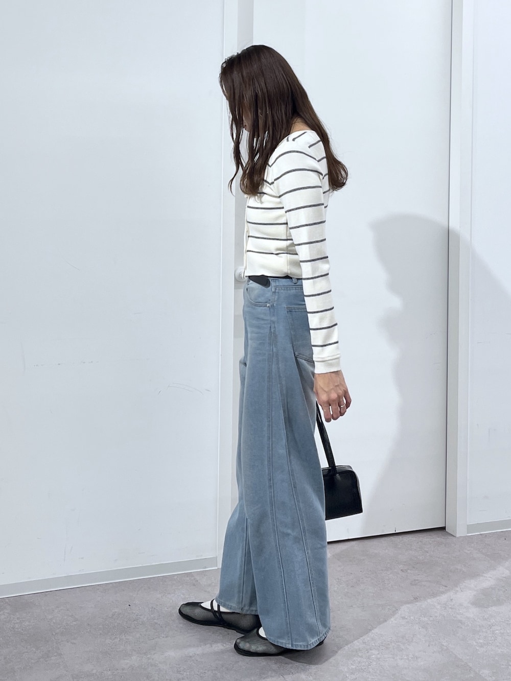 ブラック系のショルダーバッグ、ホワイト系のニット/セーター、ブルー系のデニムパンツを着用したレディースの冬コーディネートの7枚目の写真