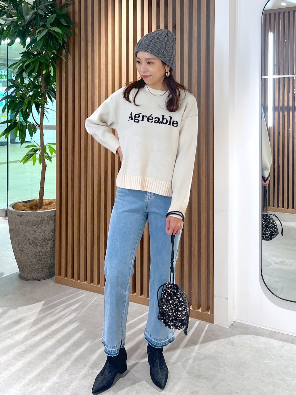 ホワイト系のニット/セーター、ブルー系のデニムパンツ、ブラック系のブーツを着用したレディースの秋コーディネートの4枚目の写真