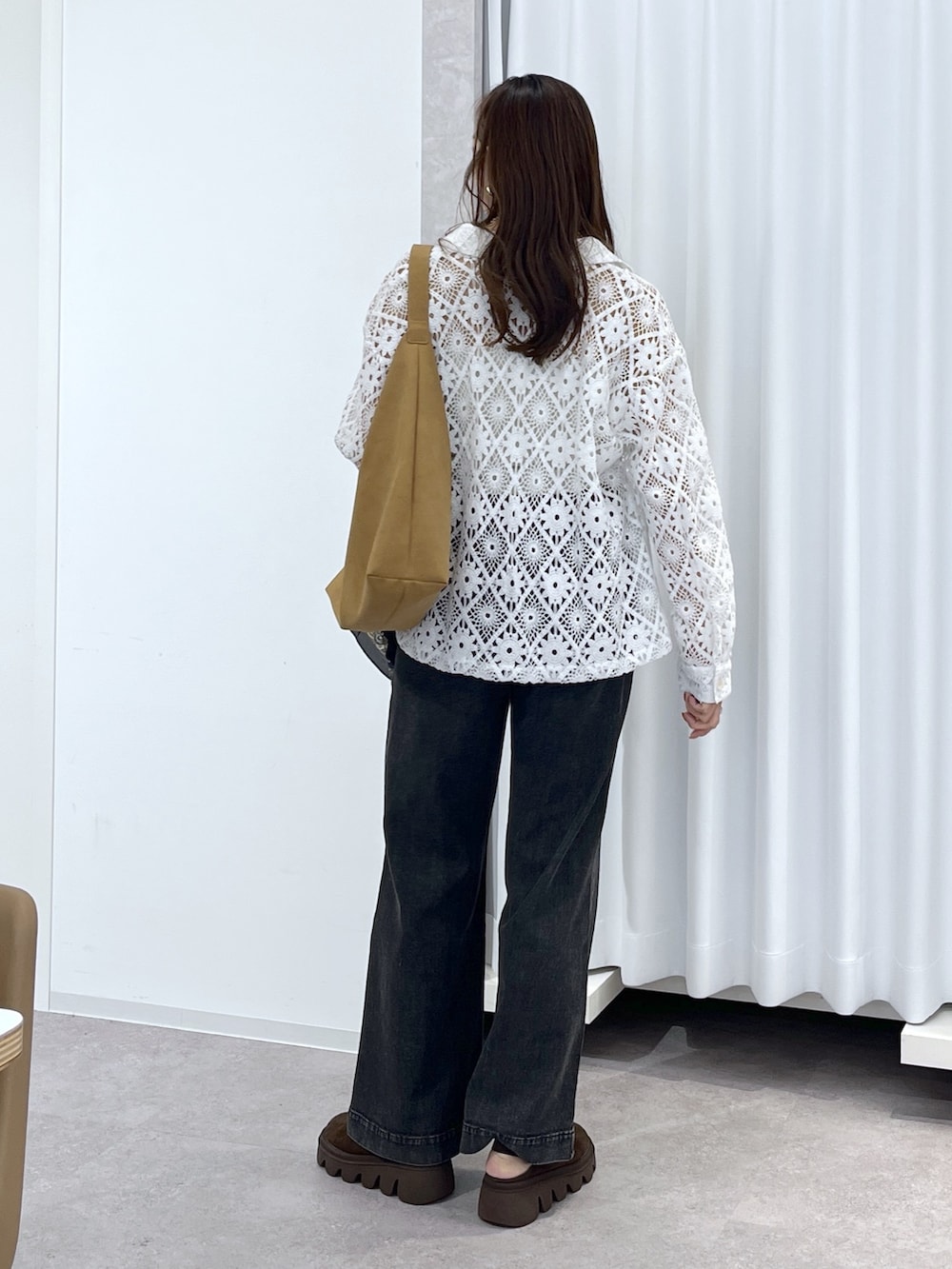 ホワイト系のブルゾン、ブラウン系のショルダーバッグ、ブラック系のデニムパンツを着用したレディースの春コーディネートの6枚目の写真