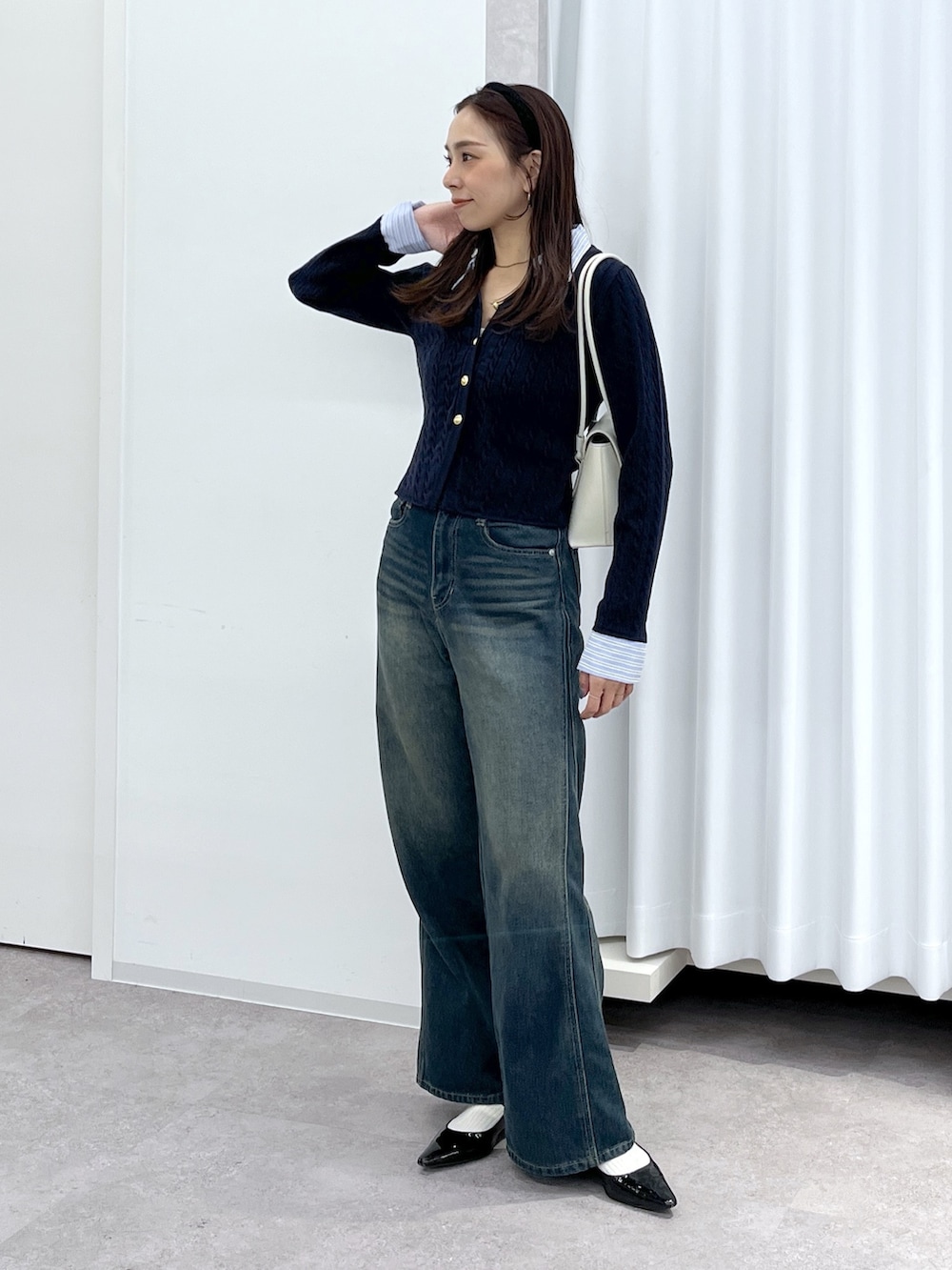 ブラック系のパンプス、ブルー系のニット/セーター、ホワイト系のショルダーバッグを着用したレディースの冬コーディネートの7枚目の写真