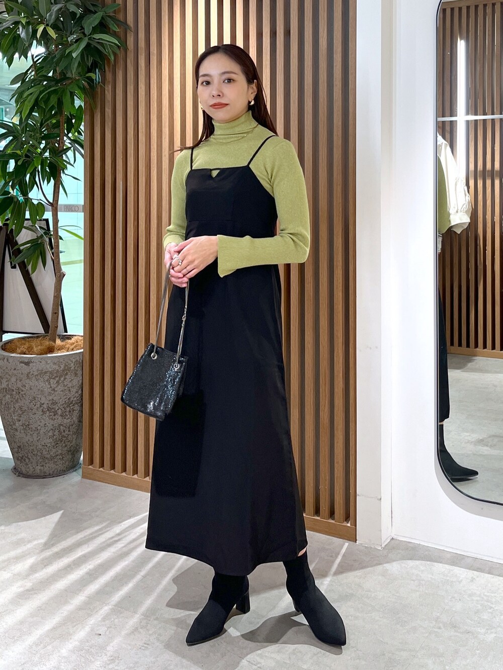 ブラック系のショルダーバッグ、ブラック系のワンピース、グリーン系のニット/セーターを着用したレディースの冬コーディネートの3枚目の写真
