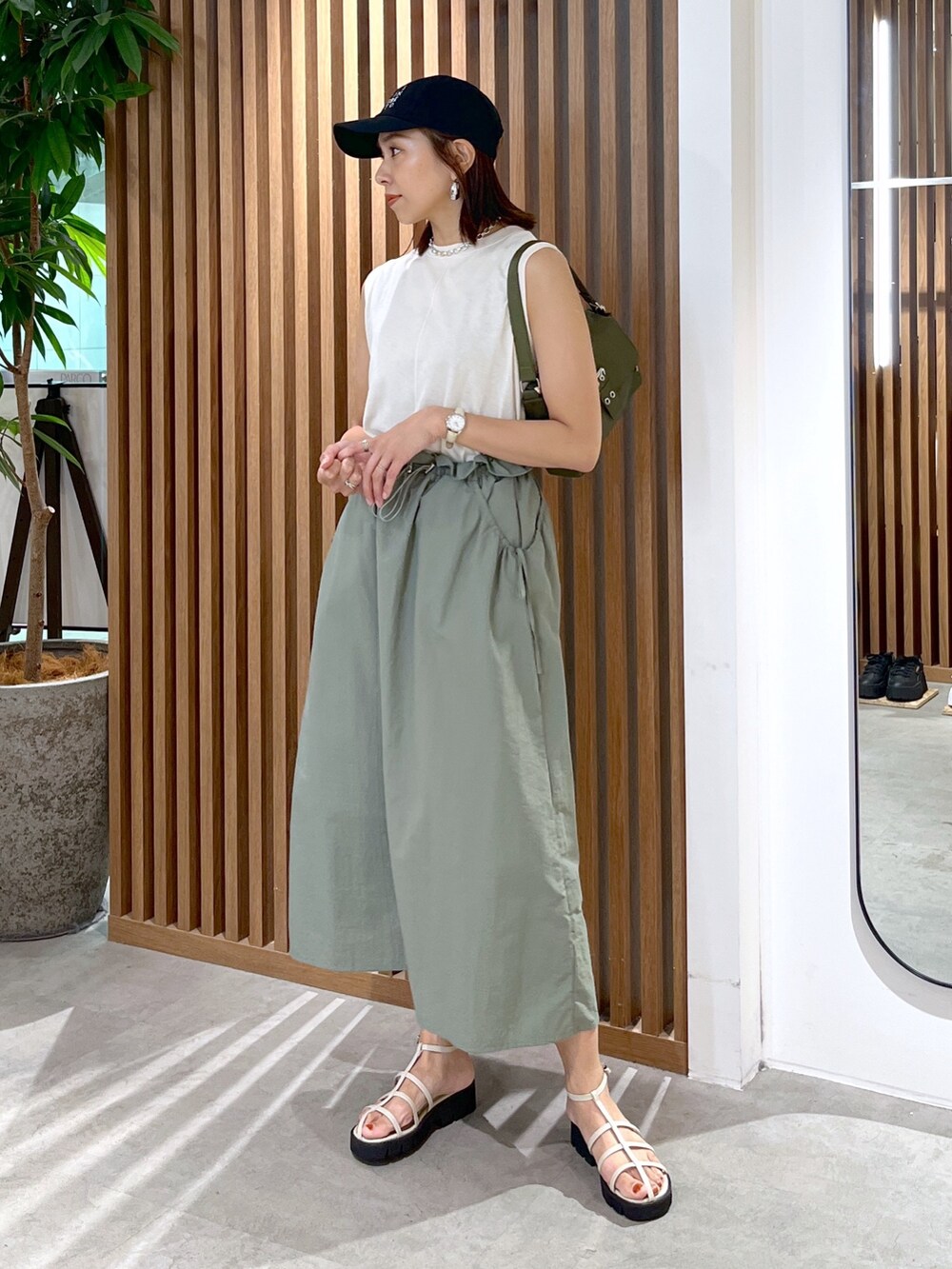 グリーン系のショルダーバッグ、グリーン系のワンピース、ホワイト系のサンダルを着用したレディースの夏コーディネートの4枚目の写真