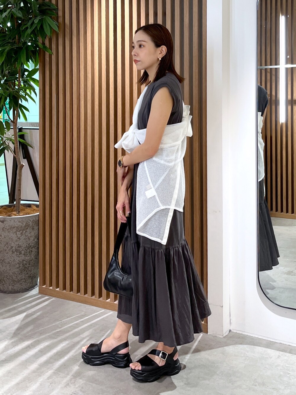 ブラック系のワンピース、ホワイト系のシャツ/ブラウス、ブラック系のサンダルを着用したレディースの夏コーディネートの2枚目の写真