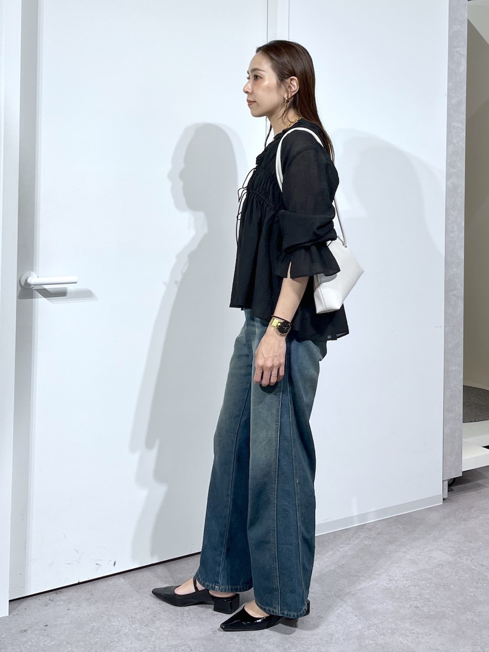 ブラック系のシャツ/ブラウス、ブルー系のデニムパンツを着用したレディースの春コーディネートの4枚目の写真