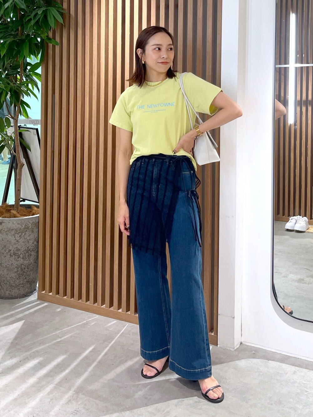 イエロー系のTシャツ/カットソー、ホワイト系のショルダーバッグ、ブラック系のスカートを着用したレディースの夏コーディネートの2枚目の写真