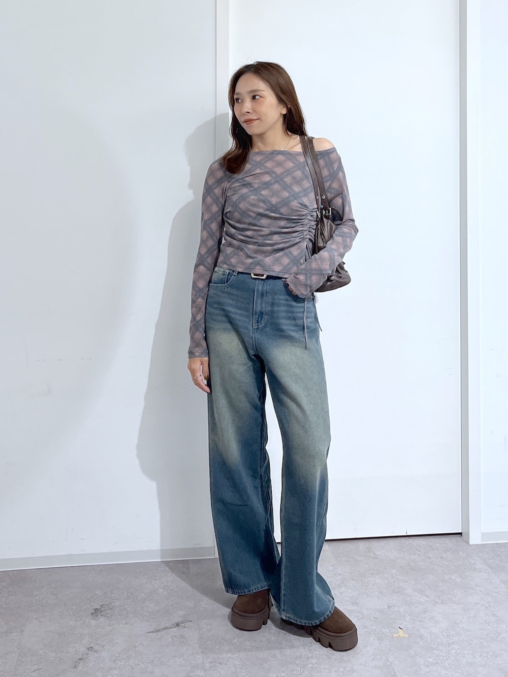 ブラウン系のショルダーバッグ、ブラウン系のTシャツ/カットソー、ブルー系のデニムパンツを着用したレディースの夏コーディネートの3枚目の写真