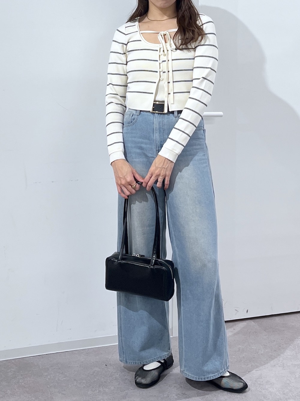 ブラック系のショルダーバッグ、ホワイト系のニット/セーター、ブルー系のデニムパンツを着用したレディースの冬コーディネートの6枚目の写真