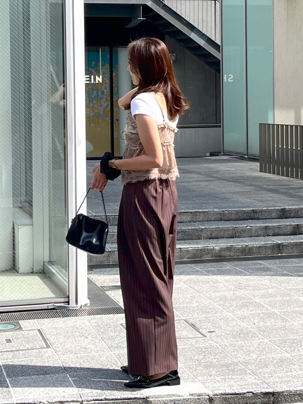 ブラック系のハンドバッグ、ブラック系のパンプス、ホワイト系のTシャツ/カットソーを着用したレディースの夏コーディネートの7枚目の写真
