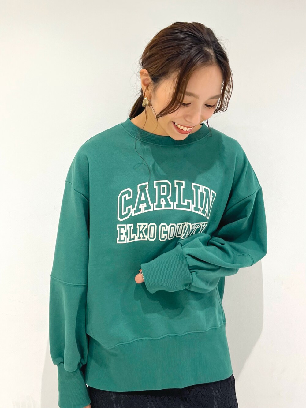 ブラック系のスカート、グリーン系のTシャツ/カットソー、ブラック系のハンドバッグを着用したレディースの秋コーディネートの3枚目の写真