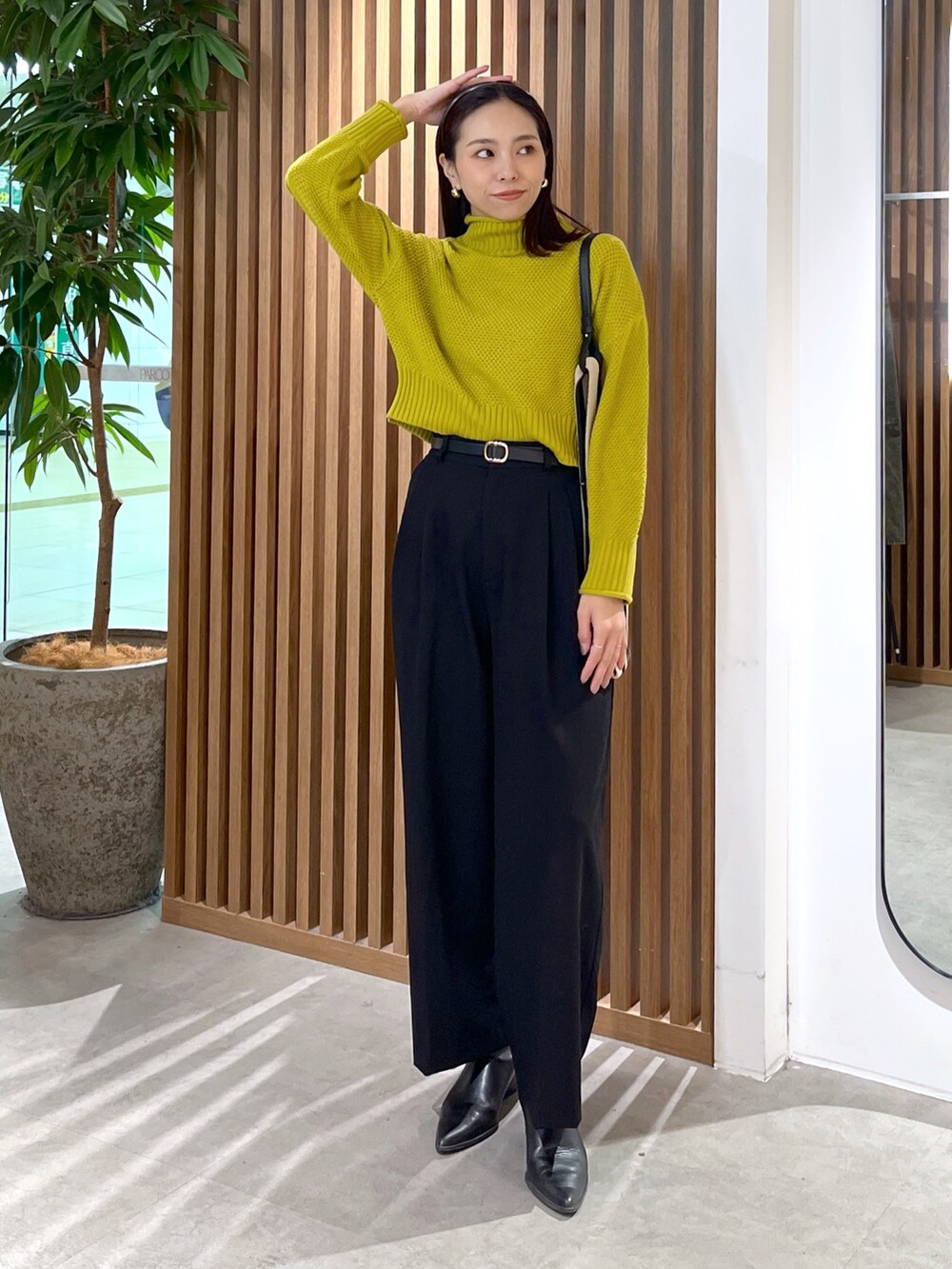 イエロー系のニット/セーター、ブラック系のスラックス、ブラック系のショルダーバッグを着用したレディースの冬コーディネートの3枚目の写真