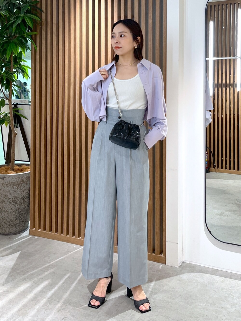 ブラック系のサンダル、グレー系のスラックス、ブラック系のショルダーバッグを着用したレディースの春コーディネートの3枚目の写真