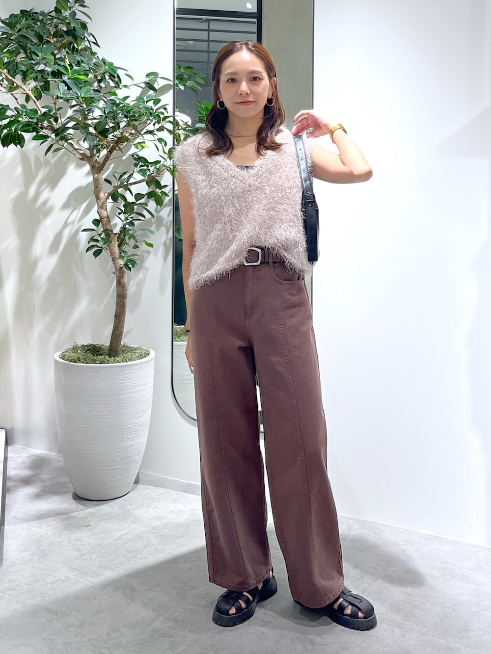 ベージュ系のニット/セーター、ブラック系のハンドバッグ、ブラウン系のデニムパンツを着用したレディースの夏コーディネートの2枚目の写真