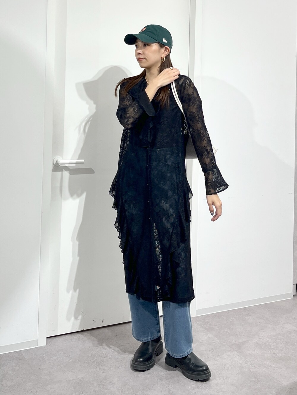 ホワイト系のショルダーバッグ、ブラック系のワンピース、ブルー系のデニムパンツを着用したレディースの冬コーディネートの2枚目の写真