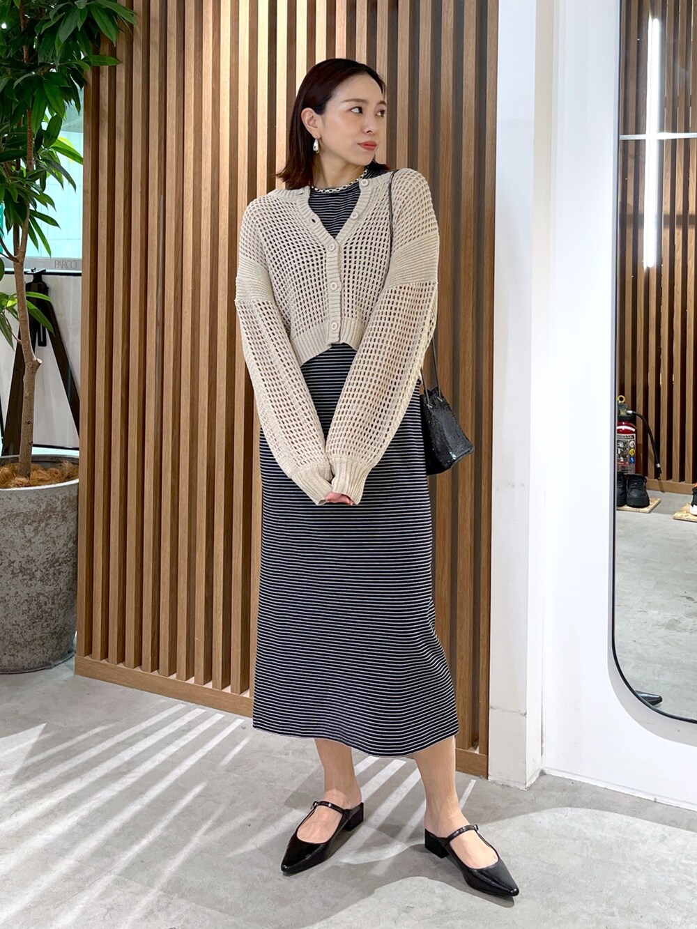 ベージュ系のカーディガン/ボレロ、ブラック系のショルダーバッグ、ブラック系のワンピースを着用したレディースの春コーディネートの5枚目の写真