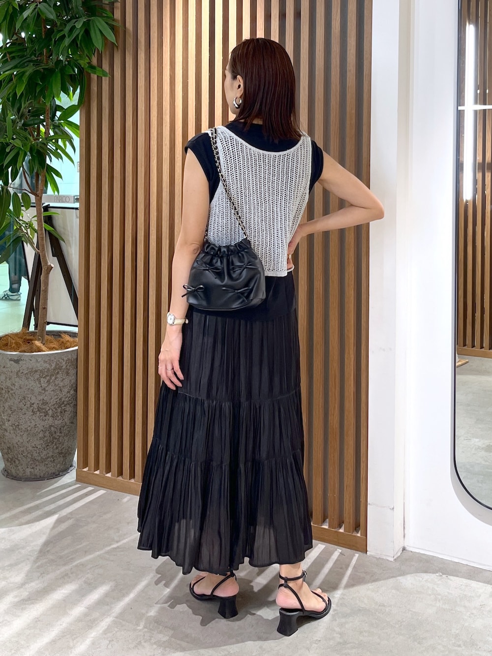 ブラック系のサンダル、ブラック系のスカート、ブラック系のショルダーバッグを着用したレディースの夏コーディネートの5枚目の写真