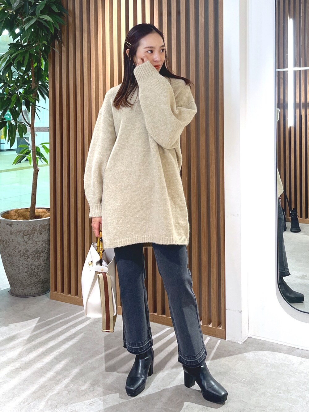 ベージュ系のワンピース、ブラック系のデニムパンツ、ホワイト系のショルダーバッグを着用したレディースの冬コーディネートの3枚目の写真