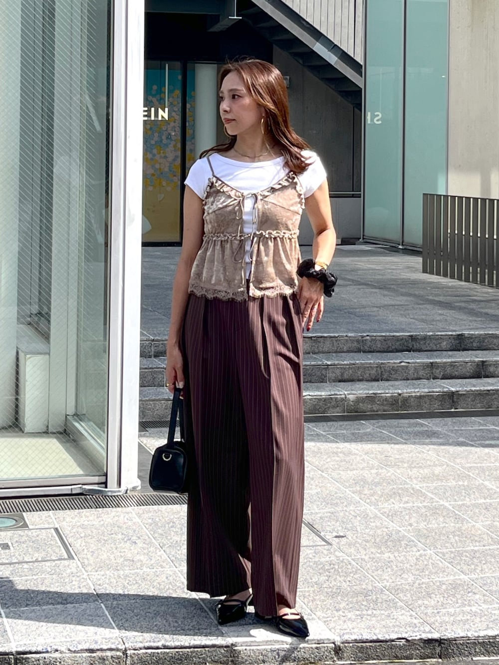ブラック系のハンドバッグ、ブラック系のパンプス、ホワイト系のTシャツ/カットソーを着用したレディースの夏コーディネートの3枚目の写真