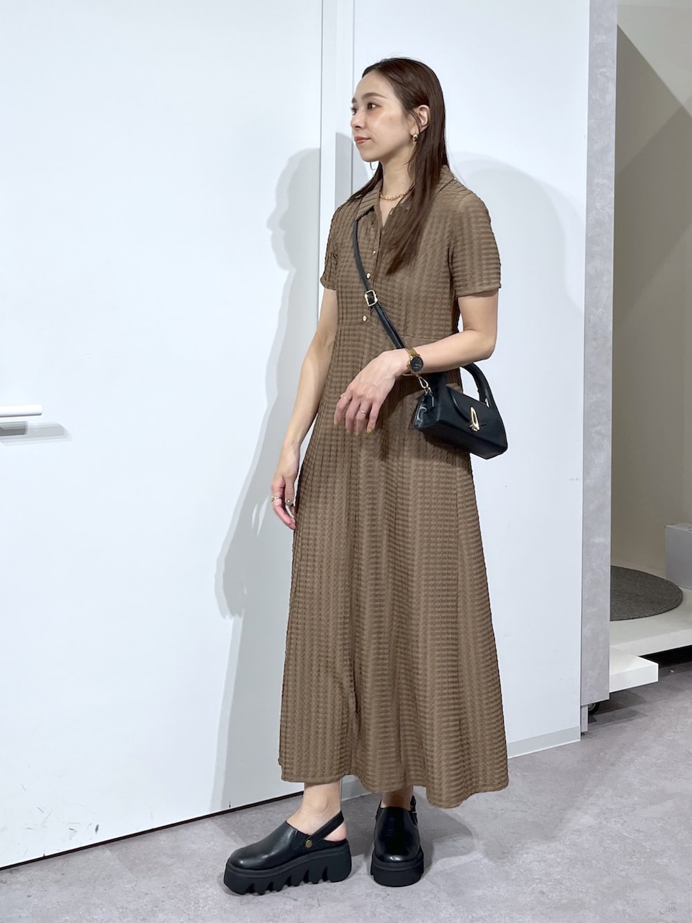 ブラック系のショルダーバッグ、ブラック系のサンダル、ブラウン系のワンピースを着用したレディースの春コーディネートの5枚目の写真