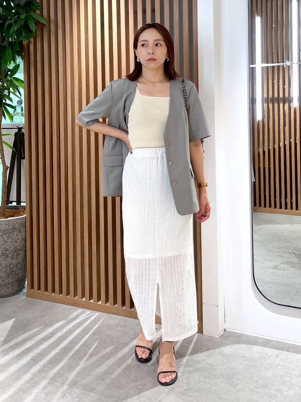 グレー系のノーカラージャケット、ブラック系のショルダーバッグ、ホワイト系のタンクトップを着用したレディースの夏コーディネートの8枚目の写真