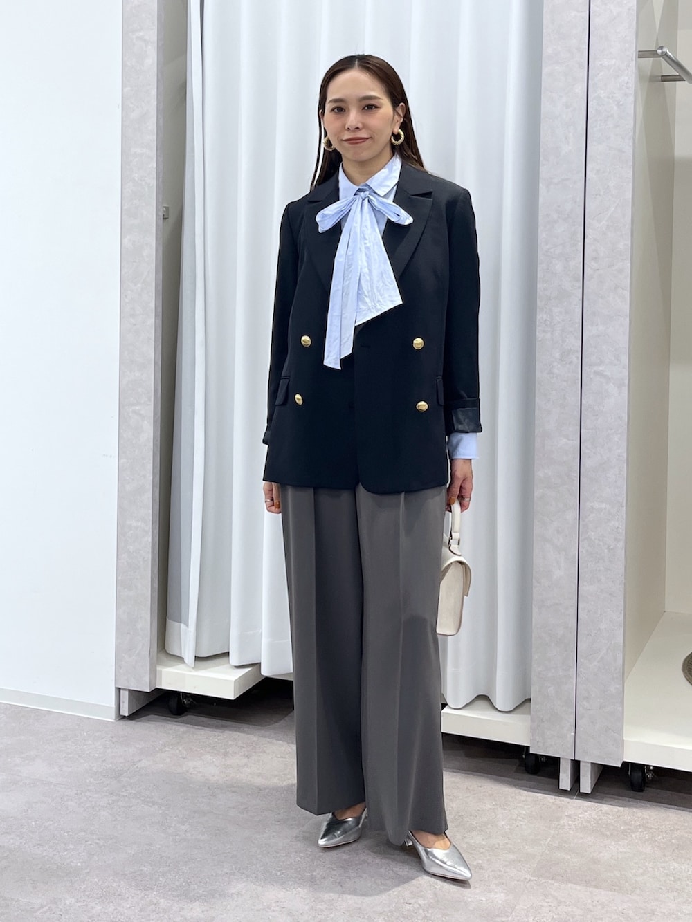 シルバー系のパンプス、グレー系のスラックス、ホワイト系のショルダーバッグを着用したレディースの冬コーディネートの3枚目の写真