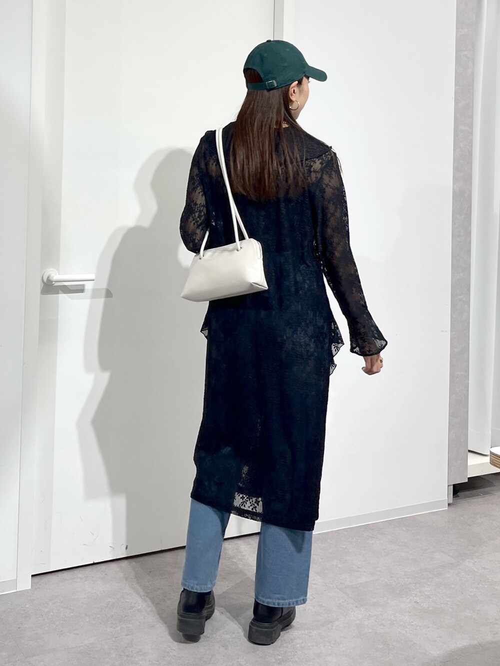 ホワイト系のショルダーバッグ、ブラック系のワンピース、ブルー系のデニムパンツを着用したレディースの冬コーディネートの7枚目の写真