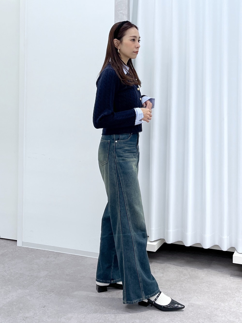 ブラック系のパンプス、ブルー系のニット/セーター、ホワイト系のショルダーバッグを着用したレディースの冬コーディネートの5枚目の写真