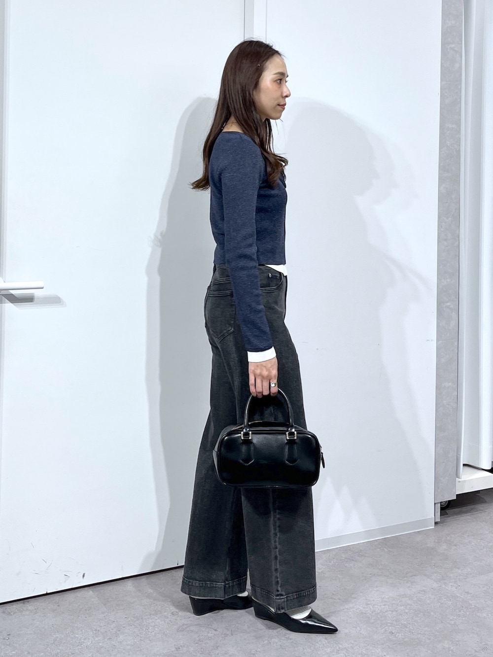 ブラック系のハンドバッグ、ブラック系のパンプス、ブラック系のデニムパンツを着用したレディースの春コーディネートの5枚目の写真