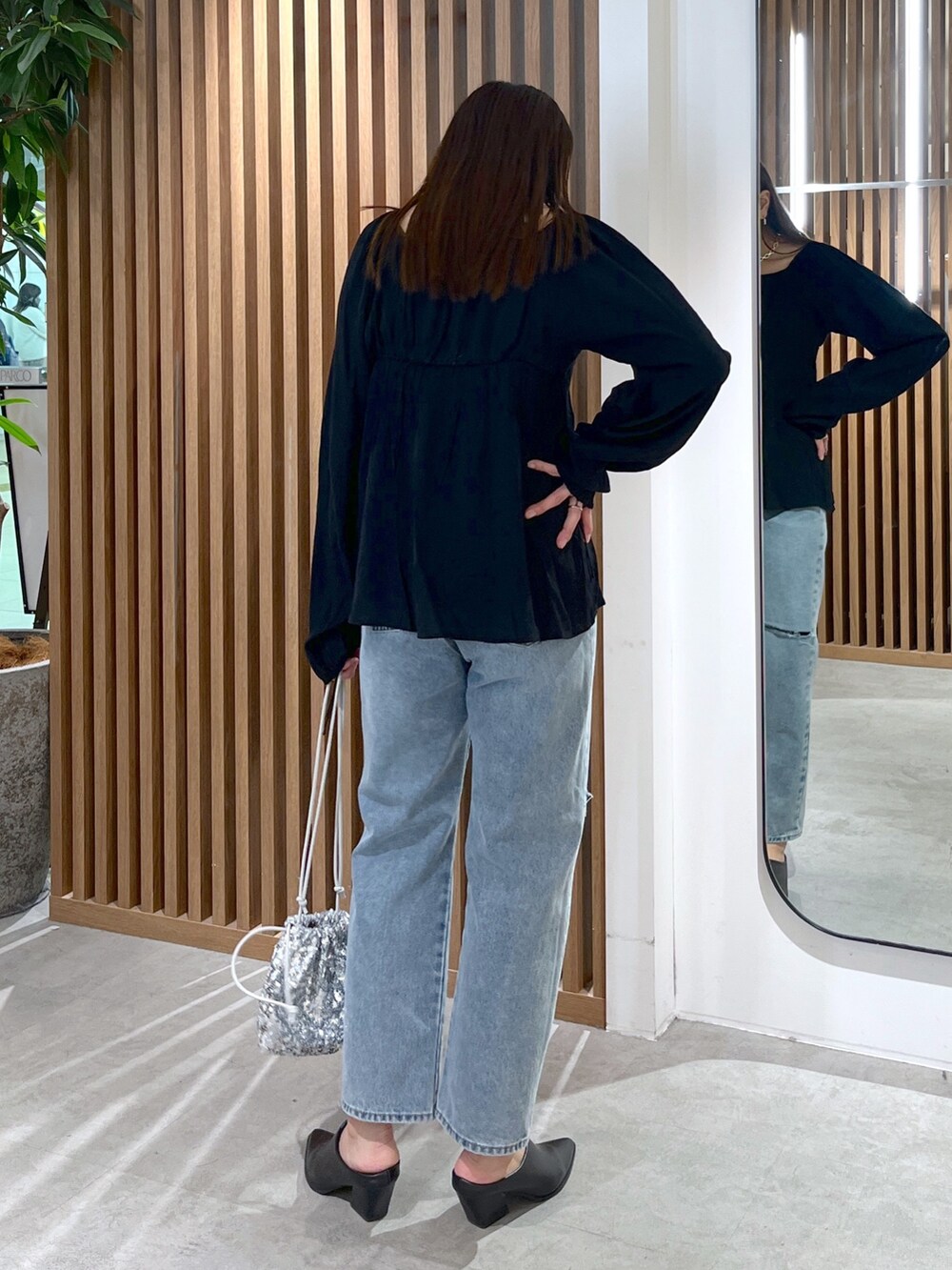 ブラック系のシャツ/ブラウス、ブルー系のデニムパンツ、シルバー系のハンドバッグを着用したレディースの冬コーディネートの5枚目の写真