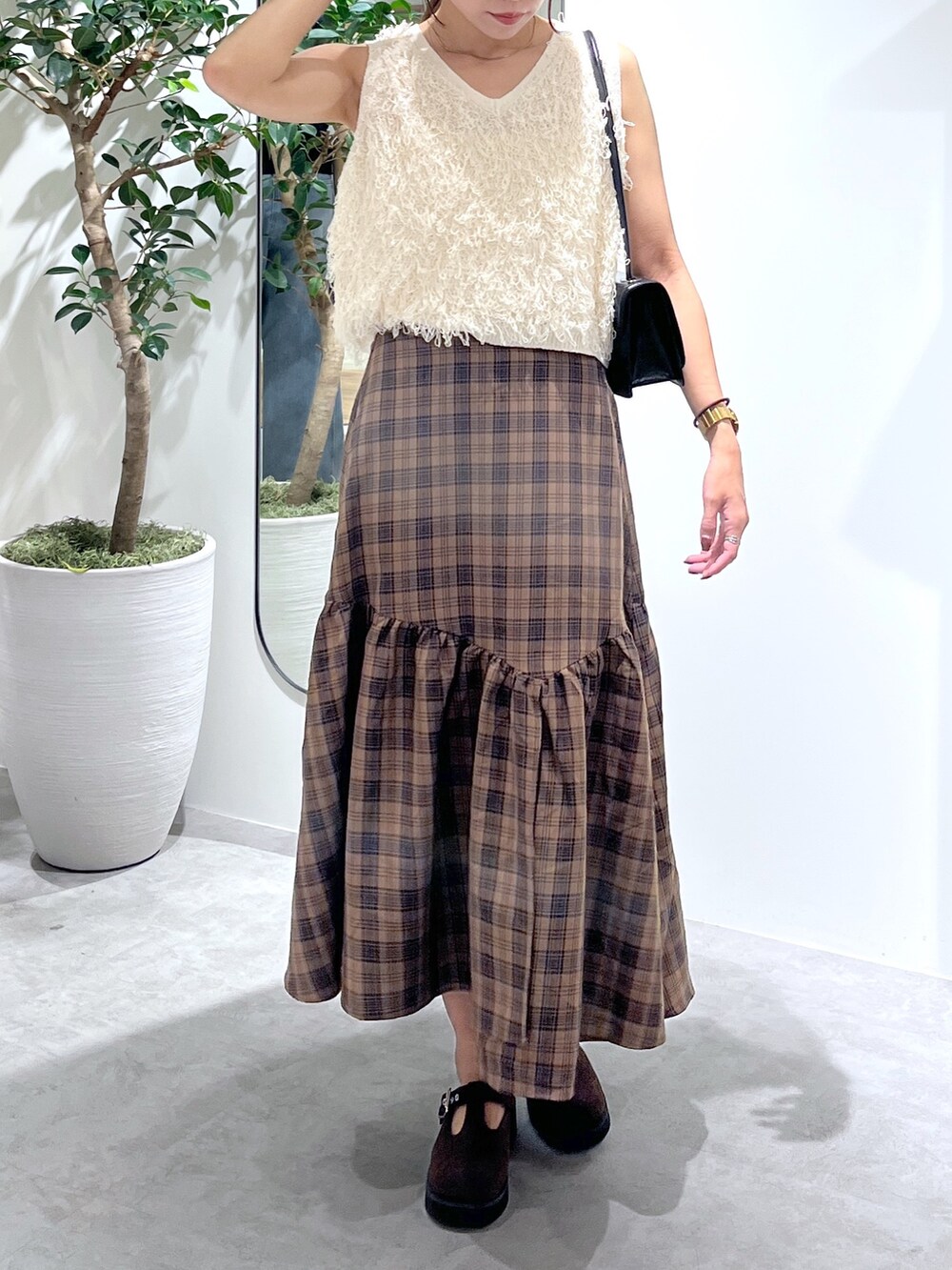 ブラウン系のシューズ、ブラック系のショルダーバッグ、ホワイト系のニット/セーターを着用したレディースの夏コーディネートの6枚目の写真