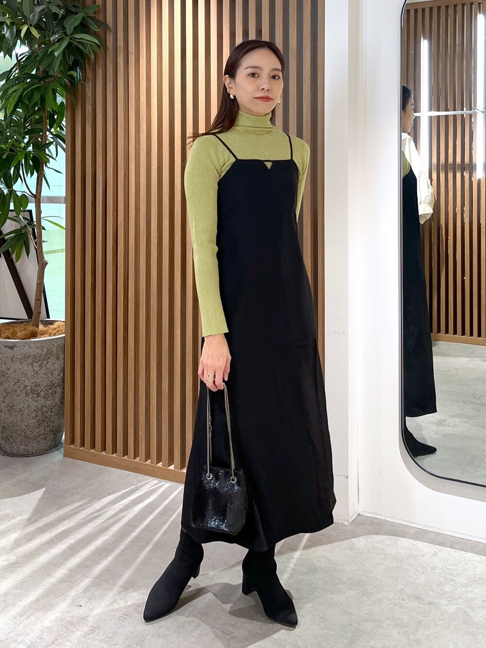 ブラック系のショルダーバッグ、ブラック系のワンピース、グリーン系のニット/セーターを着用したレディースの冬コーディネートの7枚目の写真