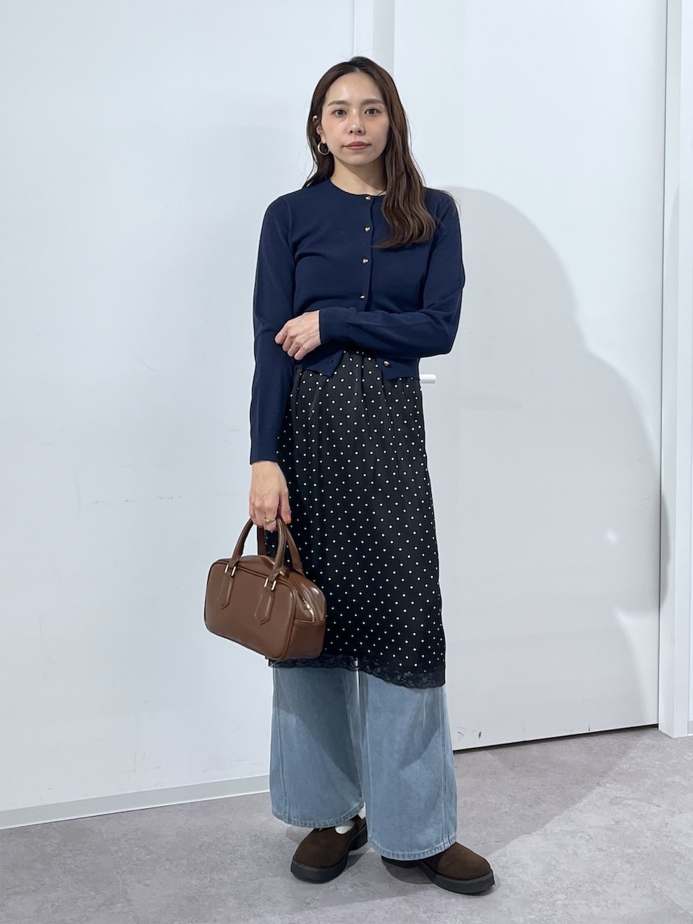 ブルー系のデニムパンツ、ブラウン系のハンドバッグ、ブラック系のスカートを着用したレディースの冬コーディネートの8枚目の写真