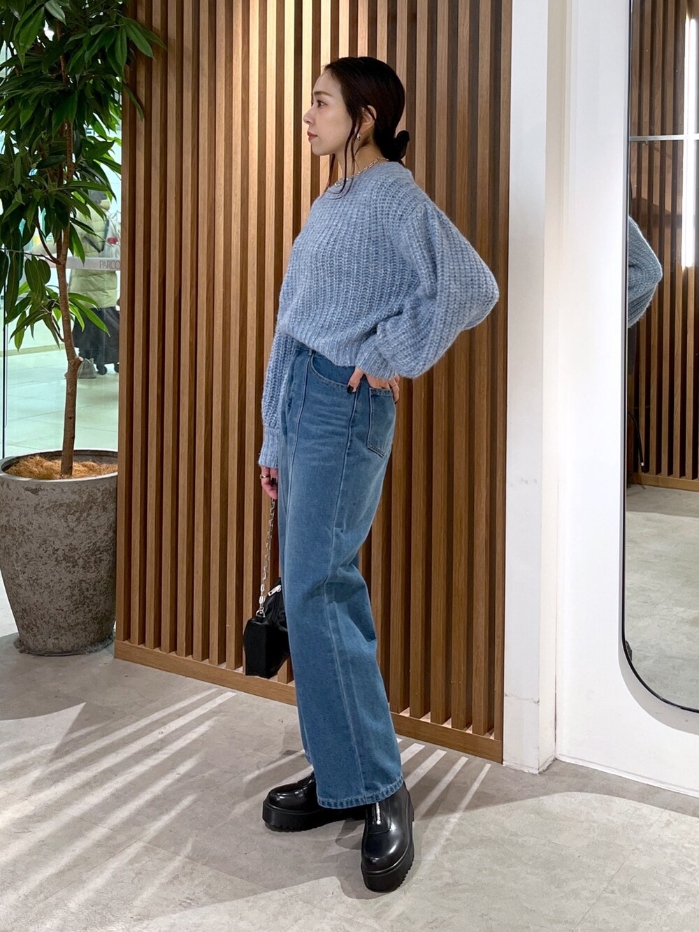 ブルー系のニット/セーター、ブルー系のデニムパンツ、ブラック系のハンドバッグを着用したレディースの冬コーディネートの5枚目の写真