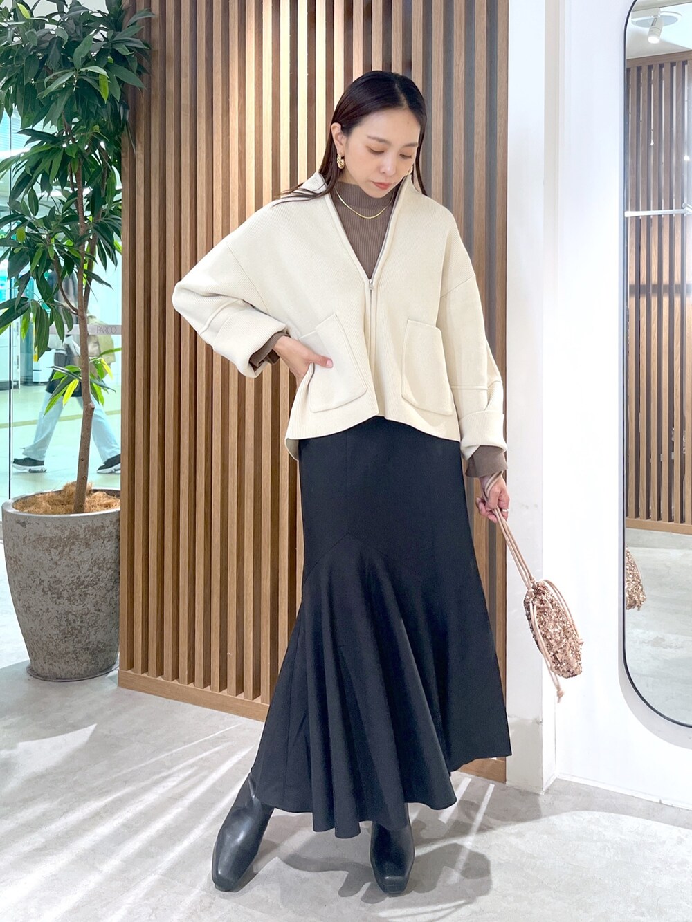 ピンク系のハンドバッグ、ホワイト系のカーディガン/ボレロ、ブラック系のスカートを着用したレディースの秋コーディネートの2枚目の写真