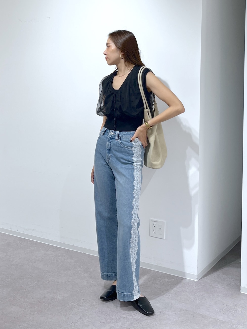 ブラック系のニット/セーター、ブルー系のデニムパンツ、ベージュ系のトートバッグを着用したレディースの夏コーディネートの8枚目の写真